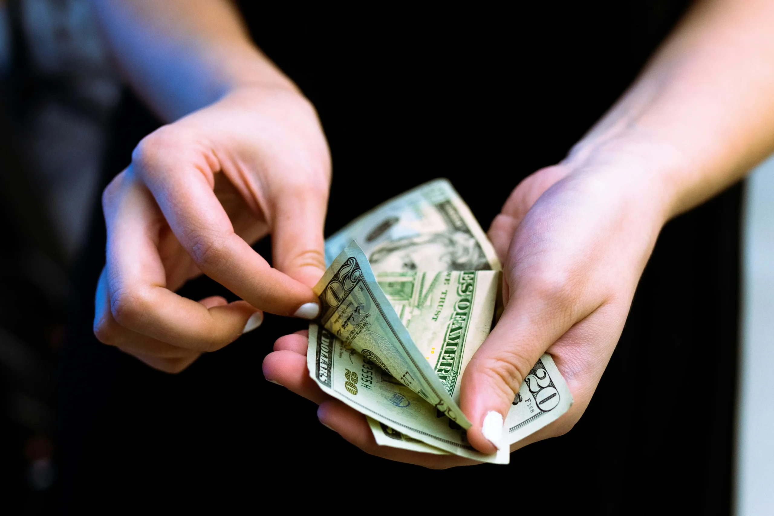 Two hands clasp money, counting each bill