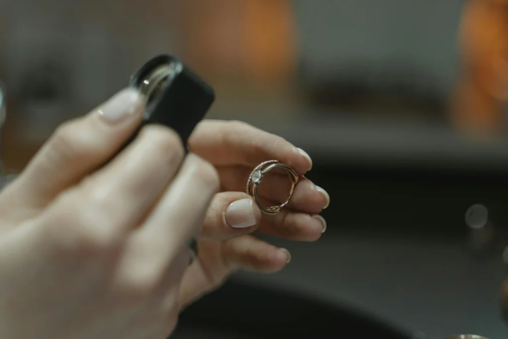 A jeweler inspects a ring with a jeweler's loupe