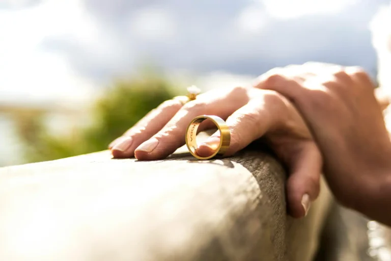 A woman's hand gently balances a man's gold band