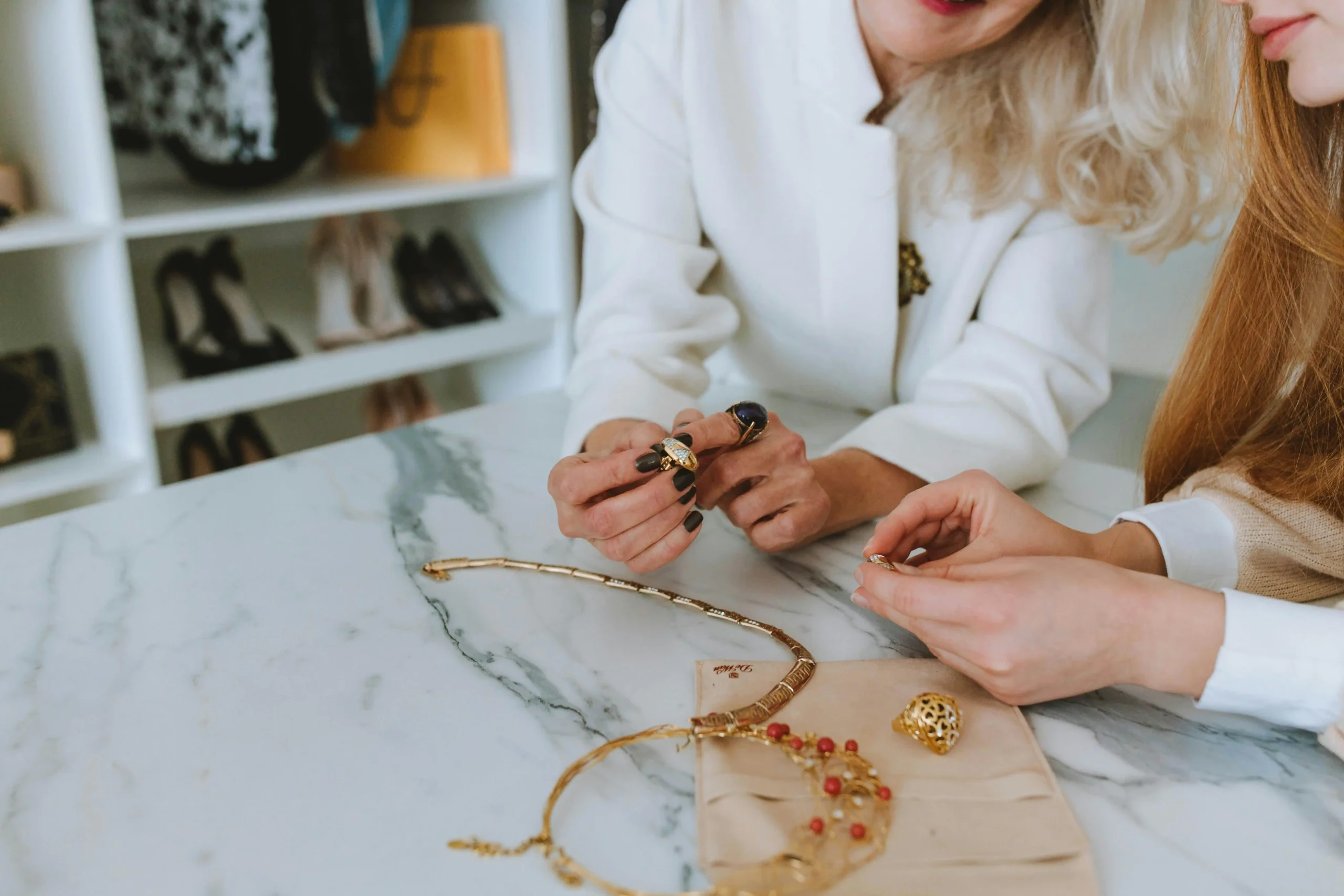 Two women inspect gold jewelry lying in front of them