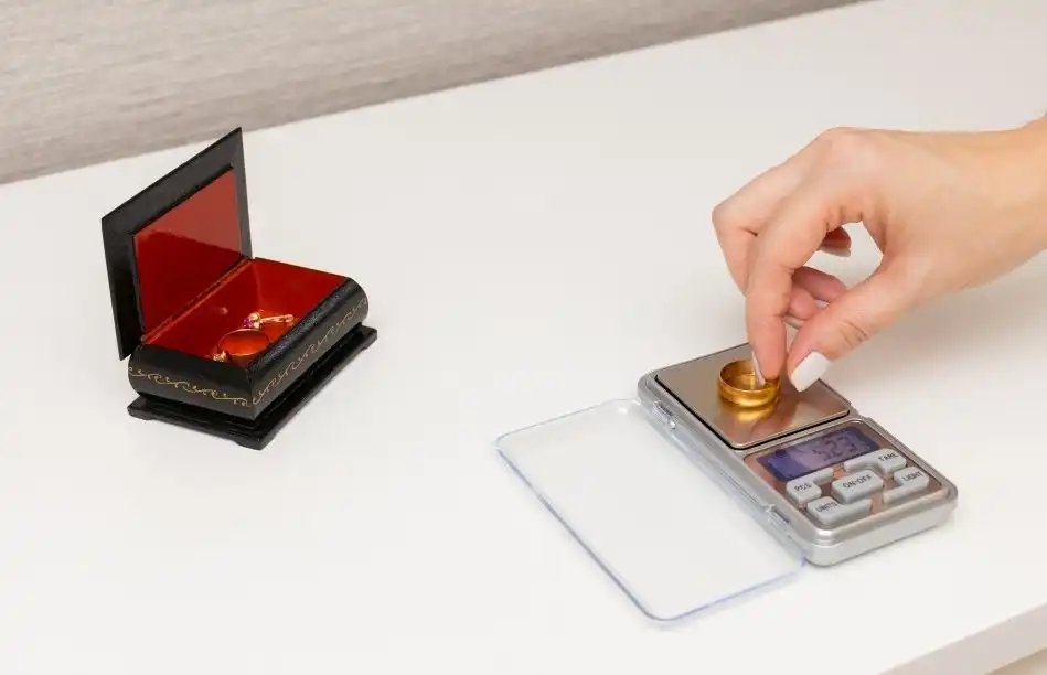 A woman weighs a gold ring on a jewelry scale