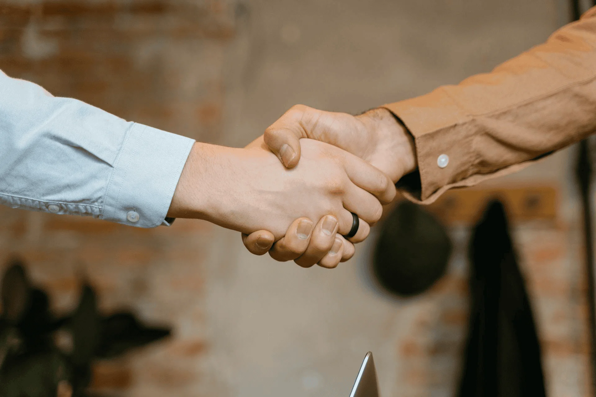 Two hands are clasped together in a handshake in the center of frame.