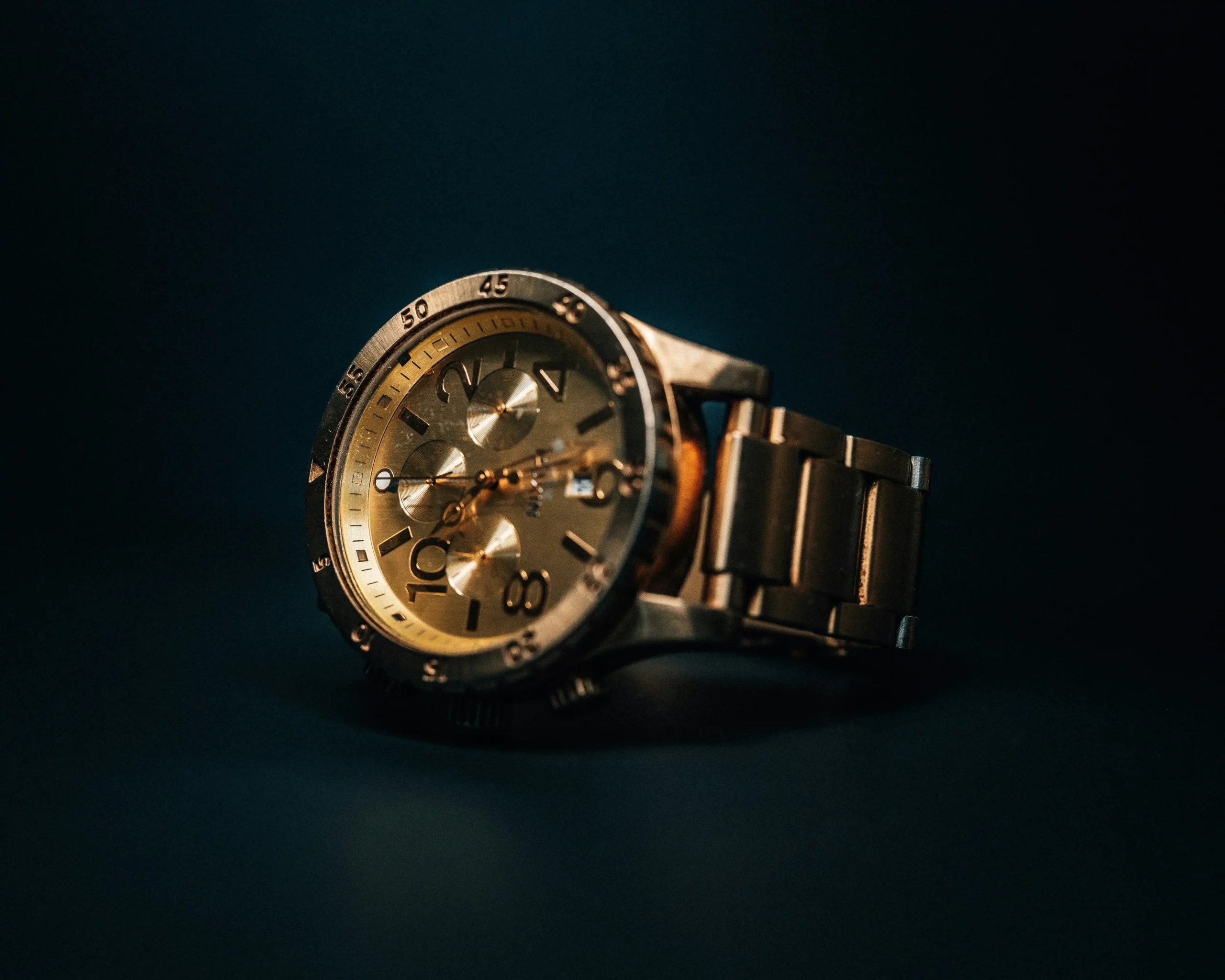 A gold watch sits atop a black background