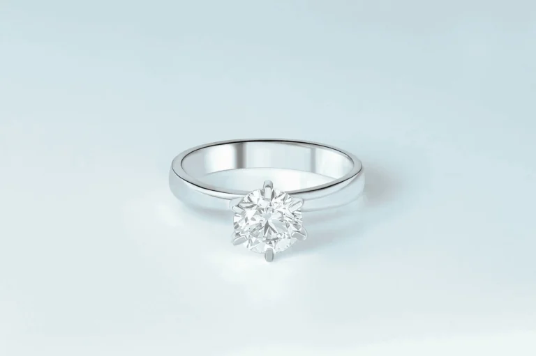 A platinum diamond solitaire sits alone on a white tabletop
