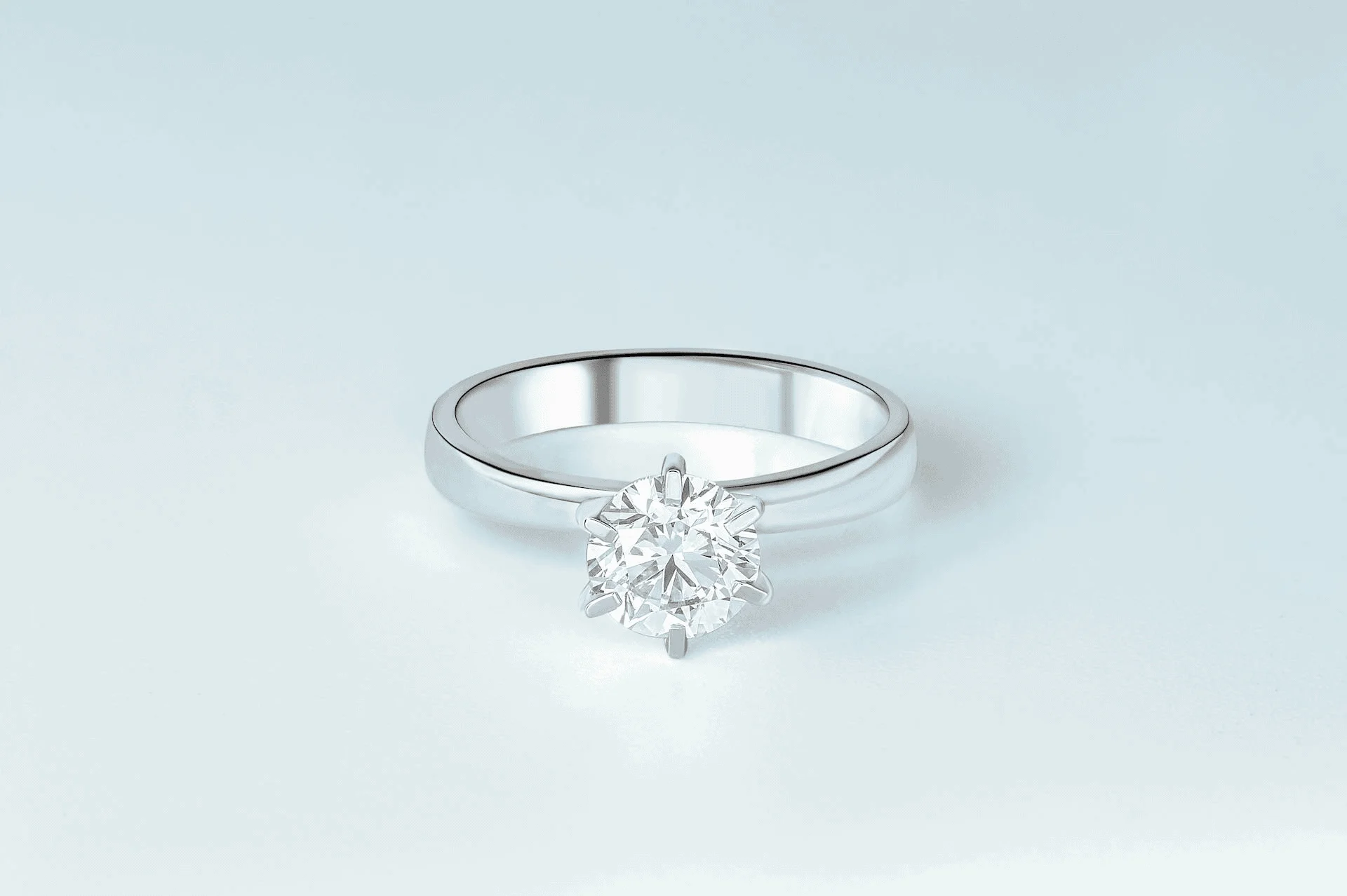 A platinum diamond solitaire sits alone on a white tabletop