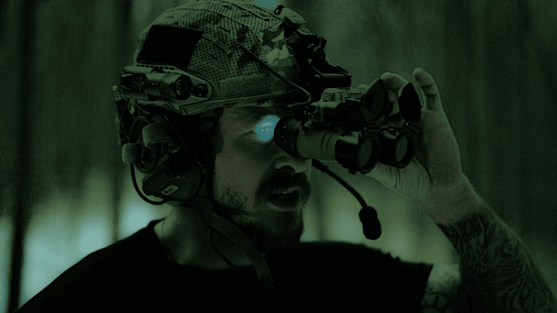 a man wearing a camo helmet looks through a set of night vision goggles