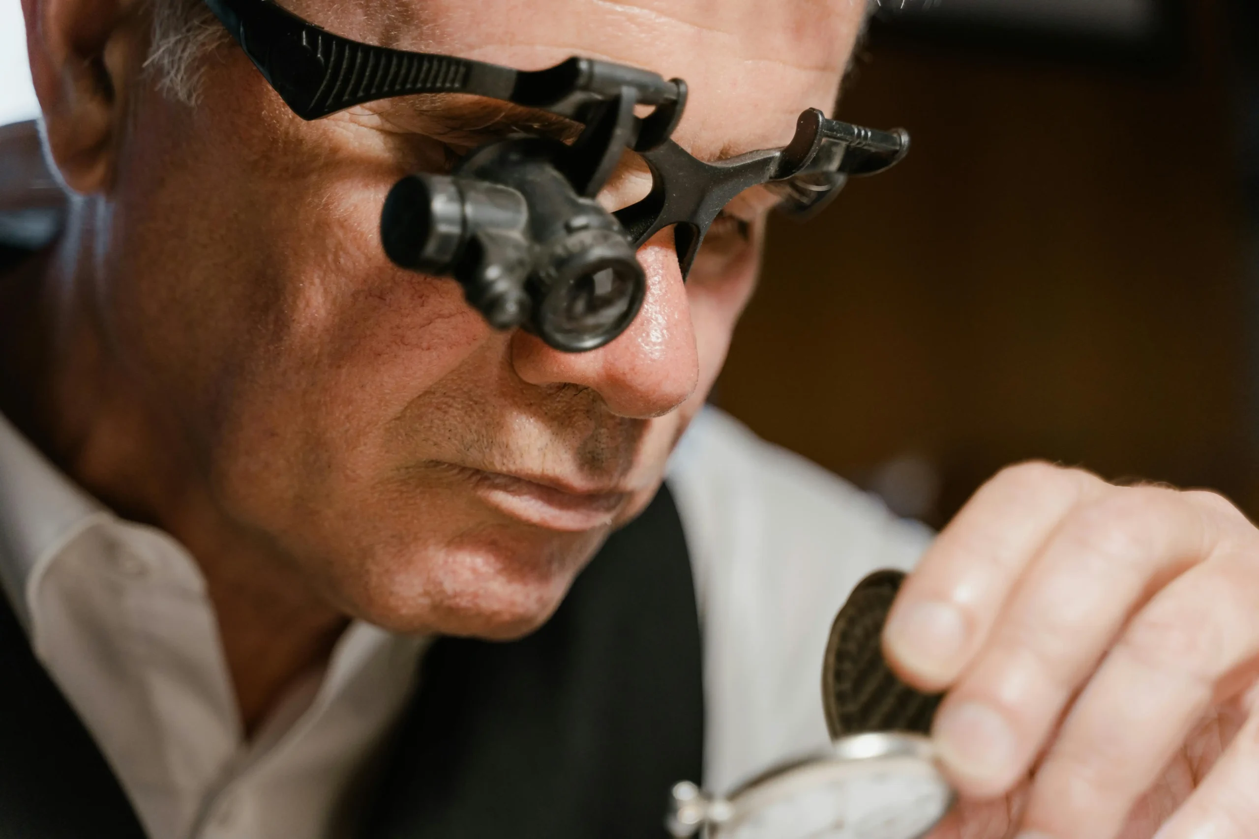 A jeweler examines a piece of jewelry with a loupe