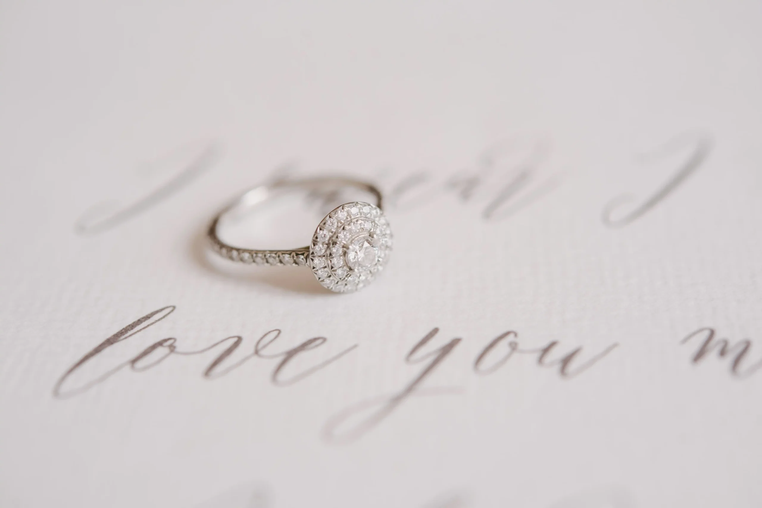 A diamond wedding band sits atop a message saying 'love you'