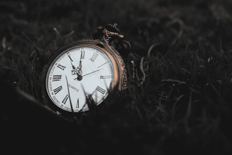 Pocket watch sits upon grass that has been turned black in post processing