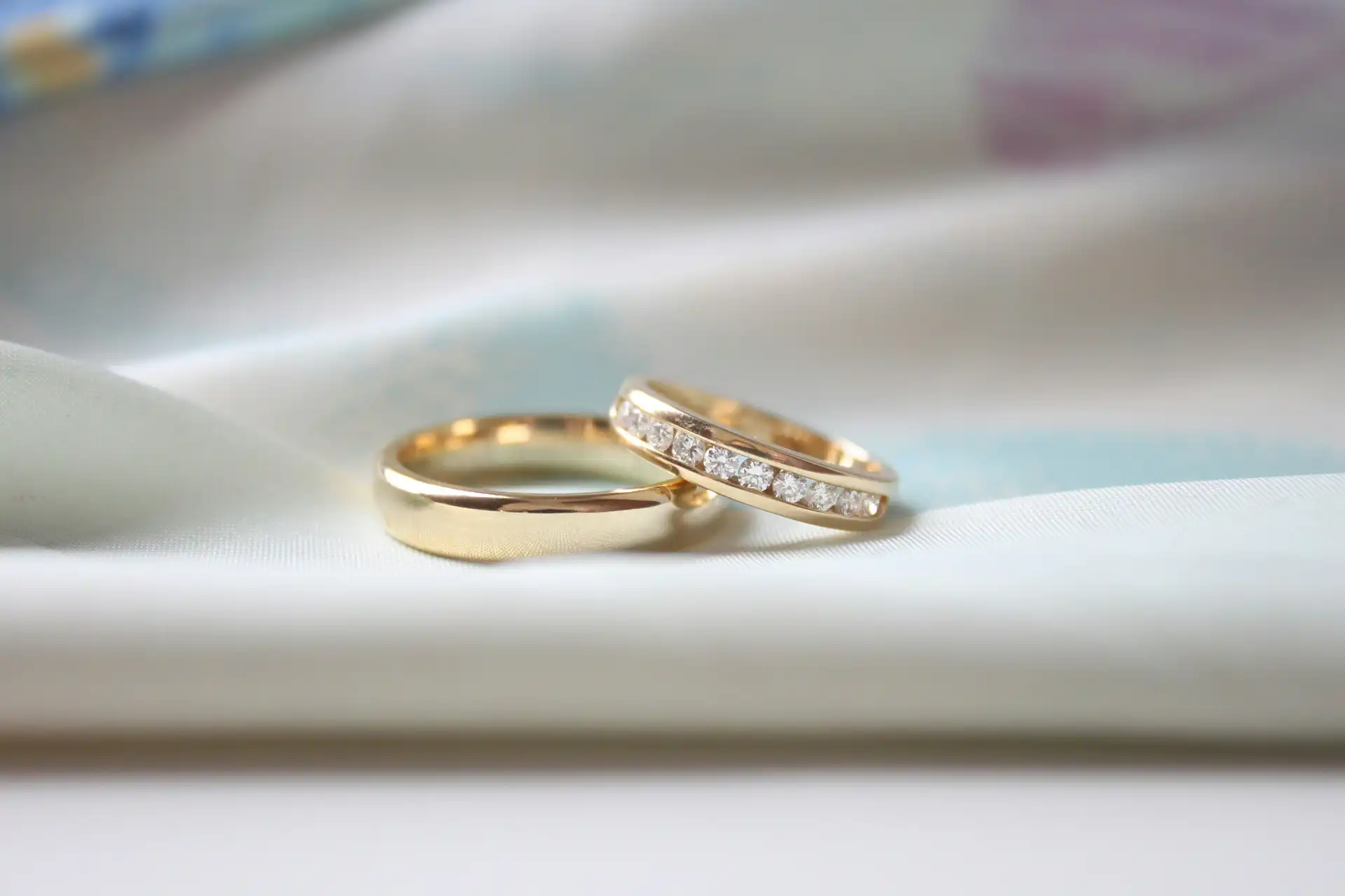 A woman and man's wedding band sit atop a piece of white fabric