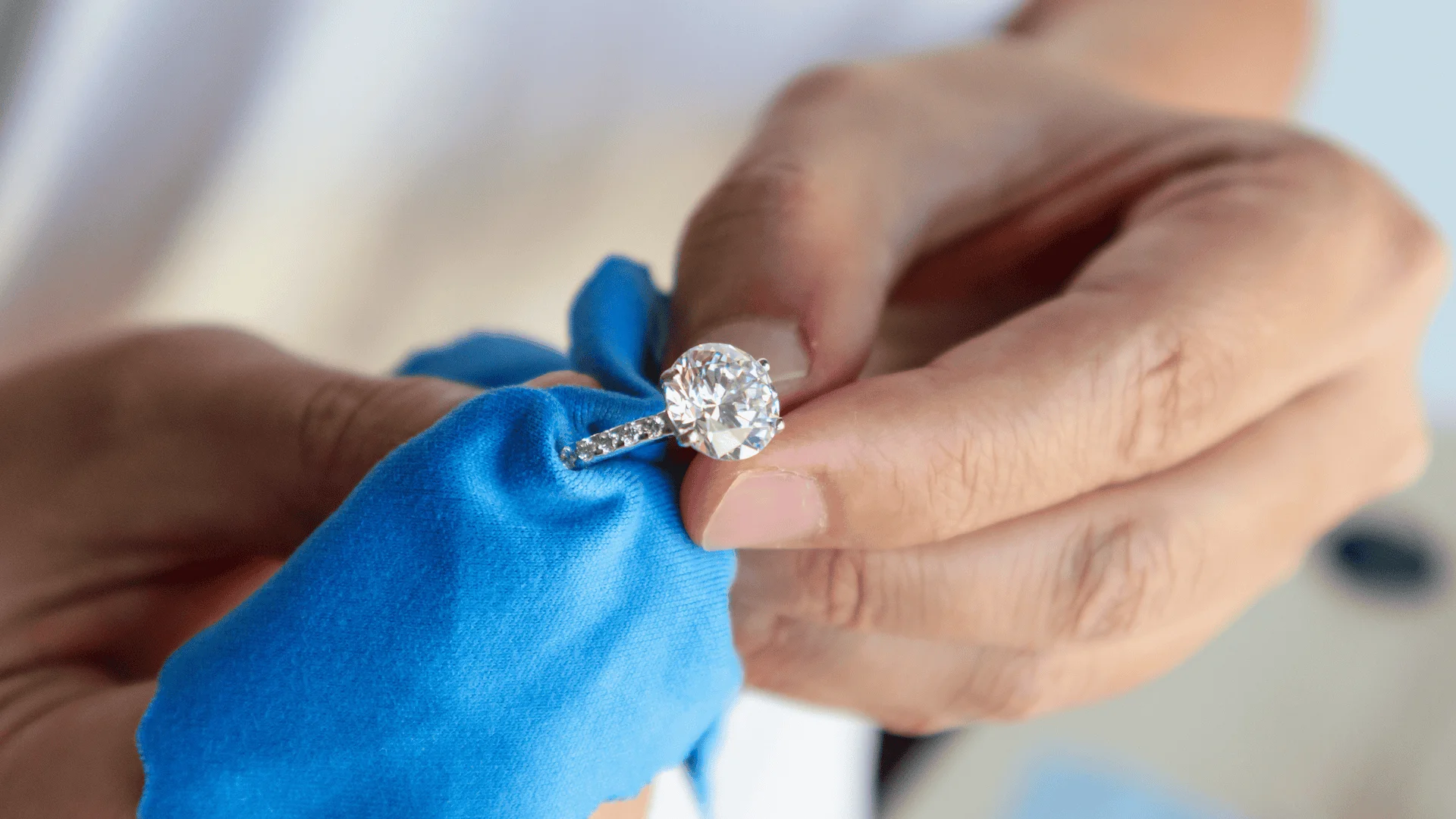a man cleans a diamond ring with a cloth