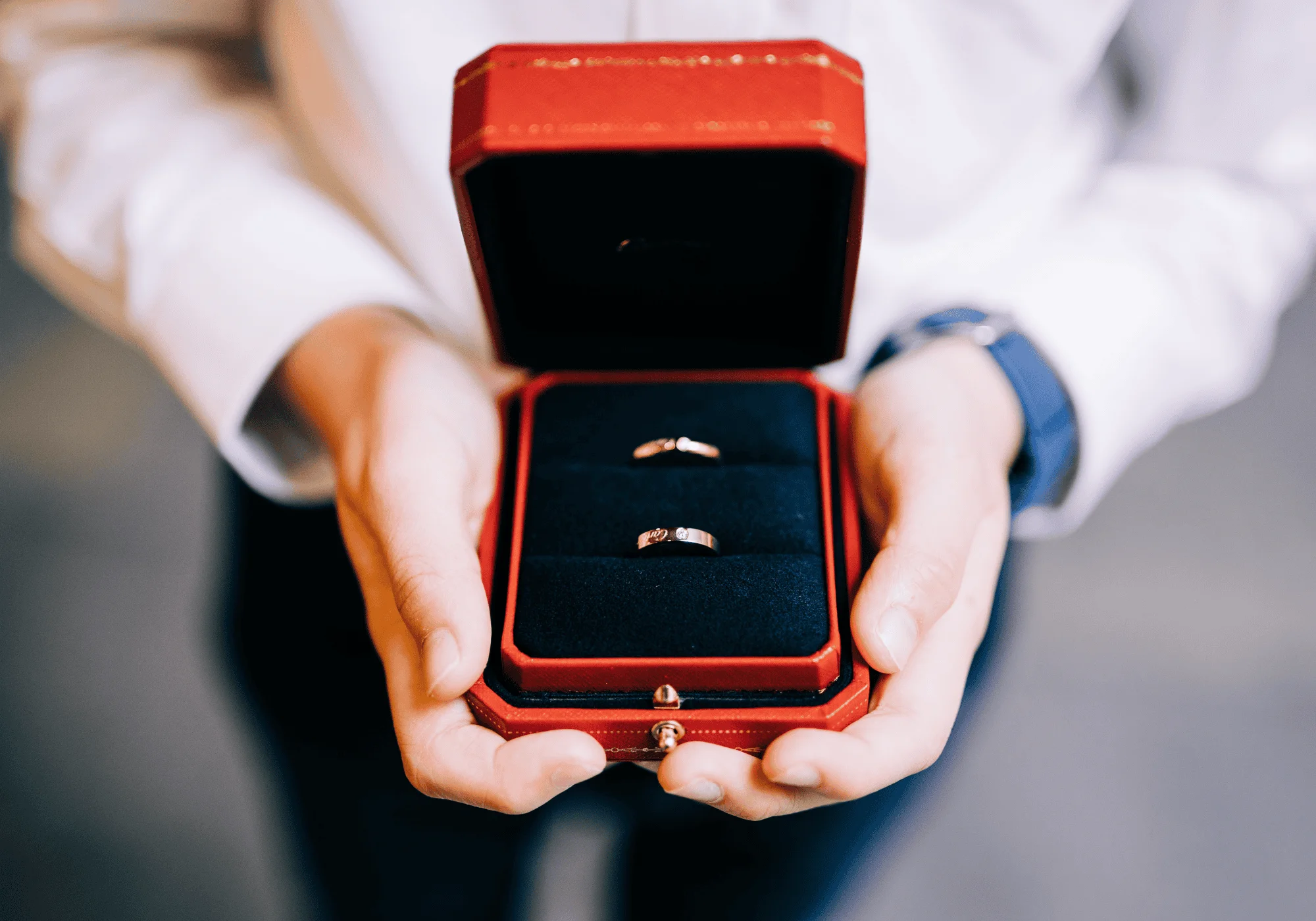 A man holds a jewelry box with two Cartier rings