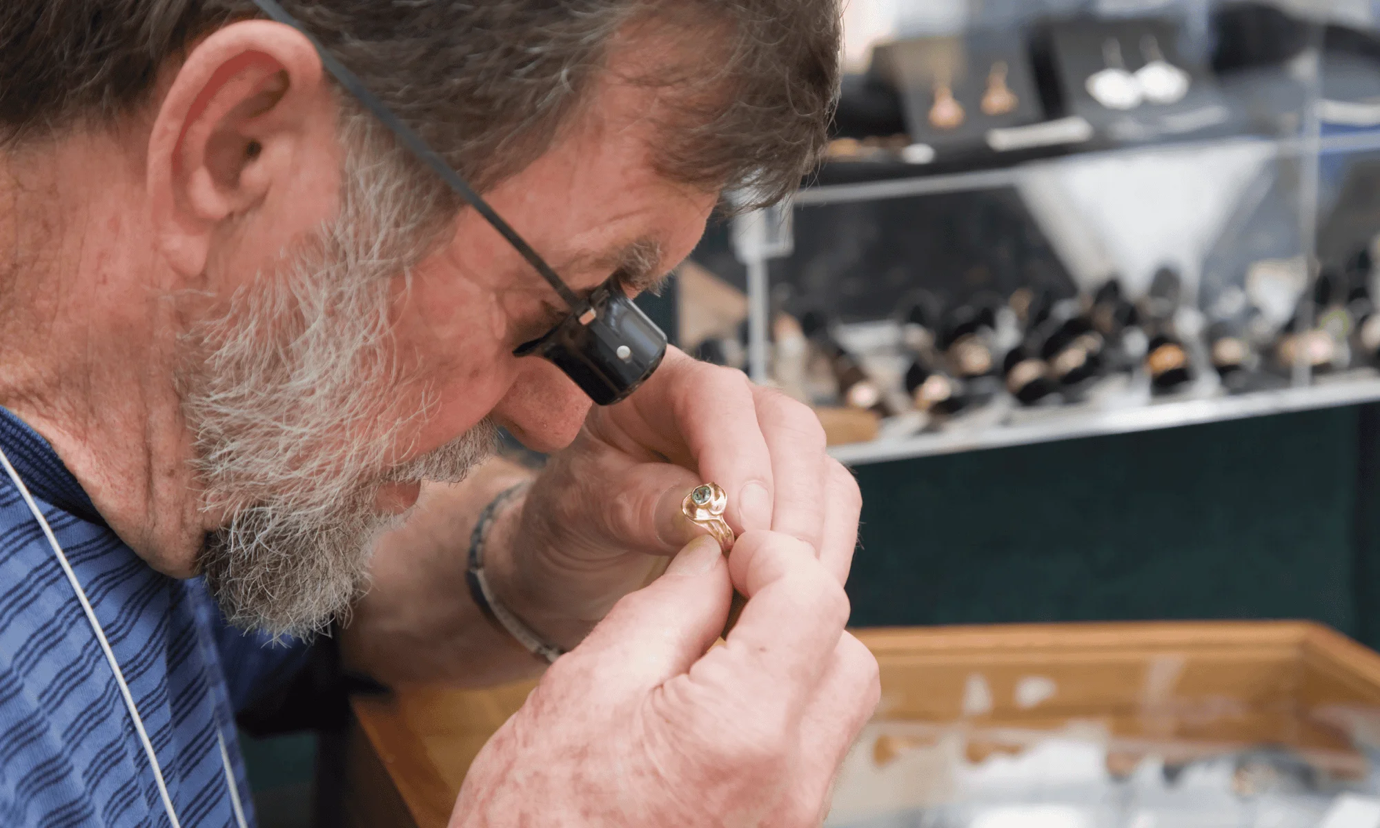 A jeweler looks through a loupe at a ring