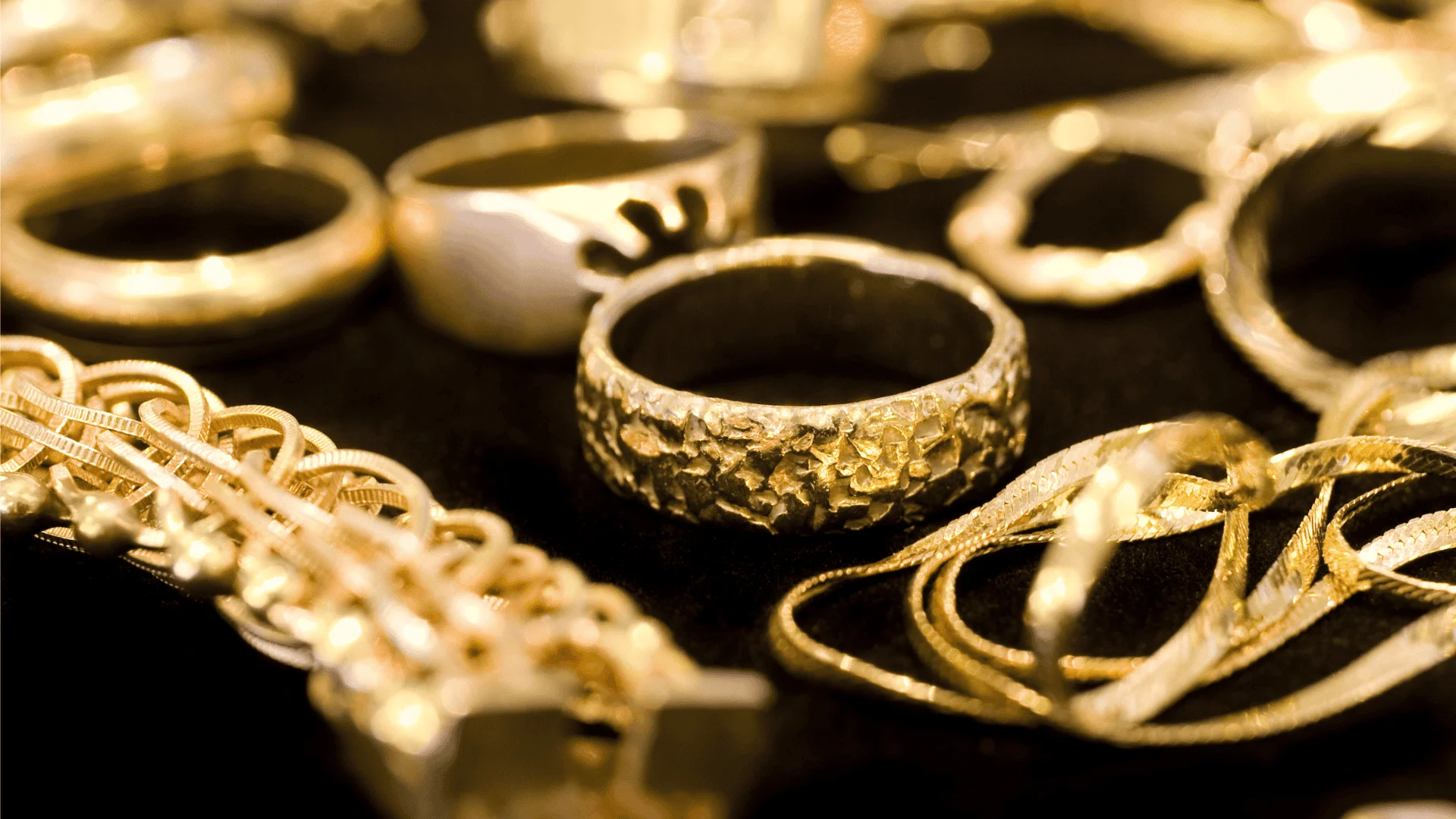 Gold jewelry laid out on a black surface